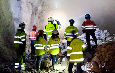 Personer i varselkläder i en tunnel under jord.
