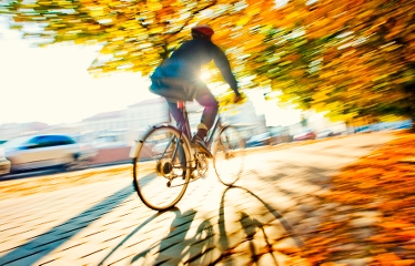 En suddig bild på en person på cykel genom stadsmiljö i orangea höstfärger.