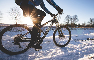 Närbild på en cyklist på mountainbike i ett vinterlandskap.