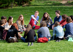 Ungdomar som sitter i en ring på en gräsmatta och pratar. Foto: Beth Macdonald på Unsplash