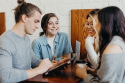 Fyra unga personer som står vid ett bord och samtalar