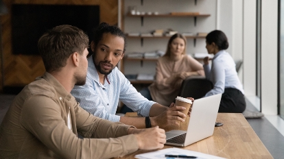 Två personer diskuterar framför en laptop på kontoret. Foto: Aleksandr Davydov