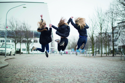Tre personer hoppar på en gata i en stad, alla med ryggen mot kameran. Foto: Scandinav Bildbyrå/Johnér
