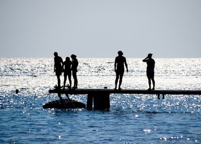 Silhuetter av personer på en brygga mot glittrande hav. Foto: Leonid Eremeychuk/Mostphotos.com