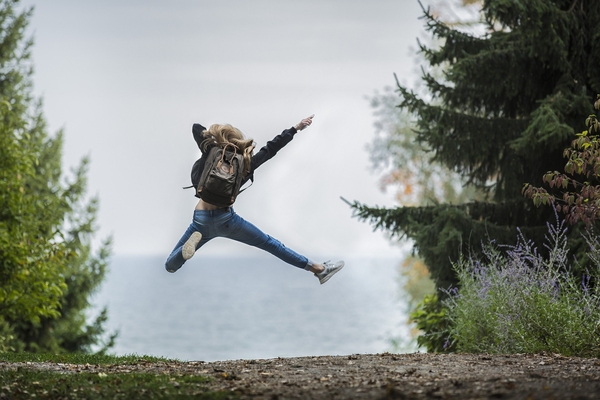 Ung person hoppar glatt i naturen med sjö i bakgrunden. Foto: Sebastian Voortman/Pexels.