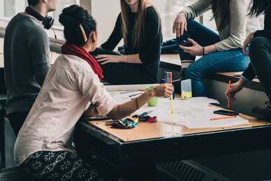 Grupp av unga vuxna som samarbetar kring ett bord fullt med papper och pennor. Foto: Pixabay/StockSnap.