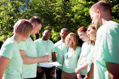 Grupp av människor i matchande tröjor som samarbetar utomhus. Foto: Andrey Popov