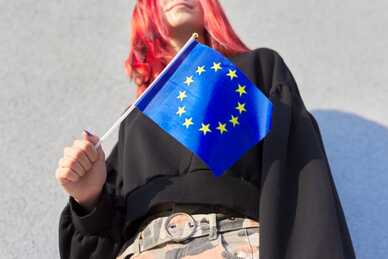 Ung person med rött hår håller i en EU-flagga.