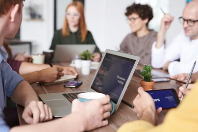 Människor som arbetar tillsammans runt ett bord med bärbara datorer. Foto: Fauxels/Pexels