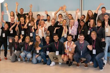 Gruppbild av leende människor som viftar med händerna. Foto: MUCF