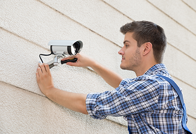 Person installerar en säkerhetskamera på en vägg utomhus. Foto: Andrey Popov
