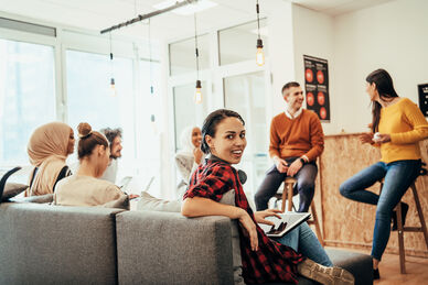 Grupp av glada unga personer i ett ljust kontorsutrymme.