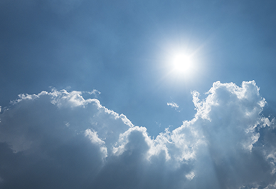 Sol över fluffiga vita moln på klarblå himmel