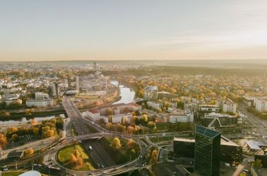Flygfoto över stad med flod, trafikknutpunkt och höstfärgade träd i morgonljus. Foto: Mostphotos.com/mnstudio