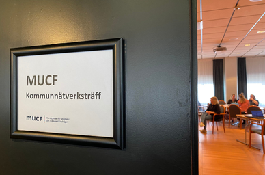 Skylt på dörr med texten MUCF Nätverksträff och personer i ett konferensrum innanför dörren. Källa: MUCF