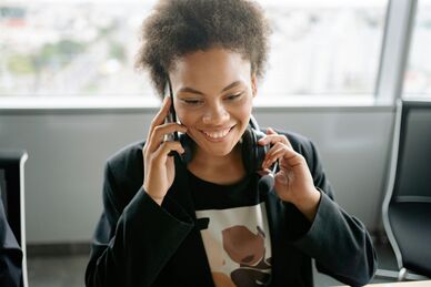 Person som ler och talar i telefon i kontorsmiljö. Foto: Yan Krukau, Pexels