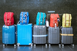 Fem resväskor och fem ryggsäckar i olika färger. Bild: Pixabay