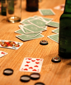 Spelkort, kapsyler, glas och flaskor på ett bord. Foto: Pixabay