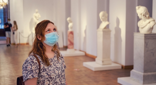 Kvinna med munskydd på museum med statyer