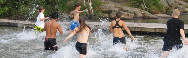 Badklädda ungdomar leker i vatten med ryggen mot fotografen.