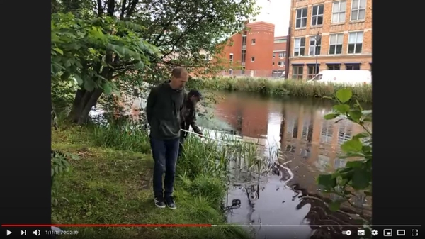 Två personer vid Mölndalsån som gör en digital vattendragsvandring.