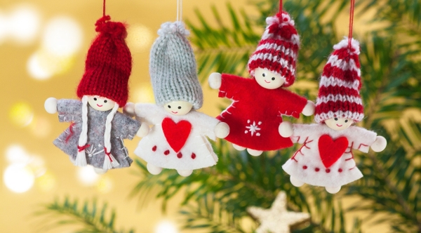Fyra julklädda prydnadsfigurer hänger i en gran.