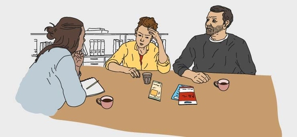 Två vuxna och ett barn sitter vid ett bord.