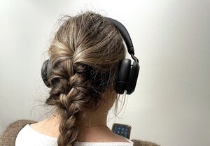 En person som har hörlurar på sig och håller i en mobil.