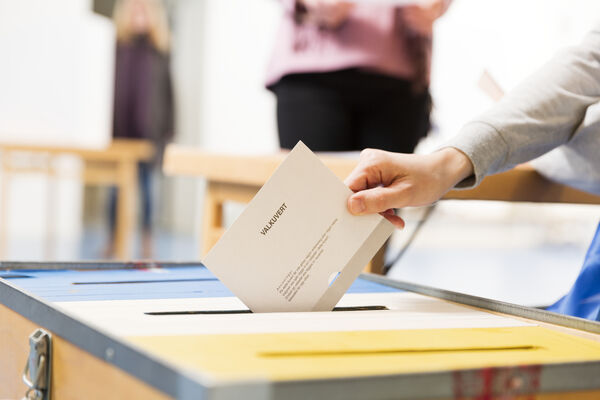 Hand som lägger ett valkuvert i en valurna.