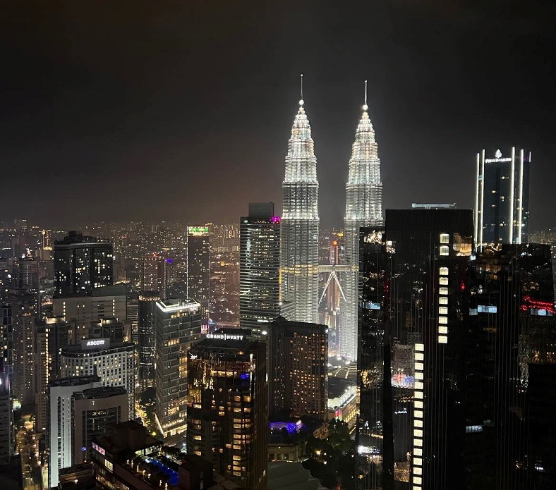 Kvällsvy över Kuala Lumpurs skyline med Petronas-tvillingtornen belysta.