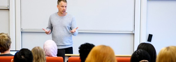 Bild på en man som föreläser inför en grupp studenter