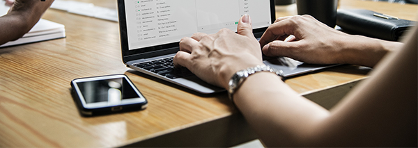 En person arbetar vid en bärbar dator på ett kontorsbord.