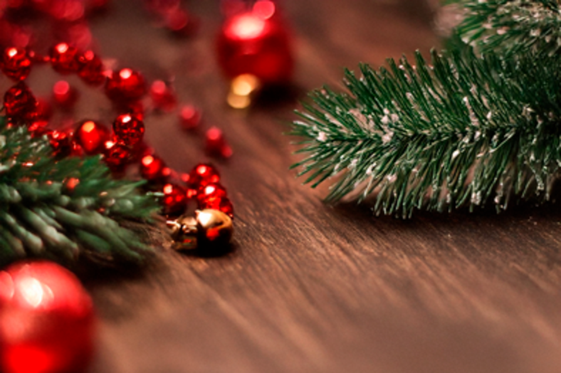 Röda julgranskulor och en grangren på ett träbord.