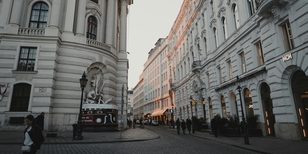 Gata i Wien vid skymningen med vandrande människor och klassisk arkitektur.