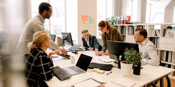 Medarbetare samarbetar och diskuterar projekt vid ett kontorsbord.