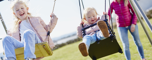 Glada barn som gungar på en lekplats en solig dag.