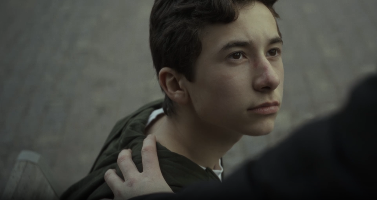 Ung man med allvarligt uttryck får tröstande hand på axeln.