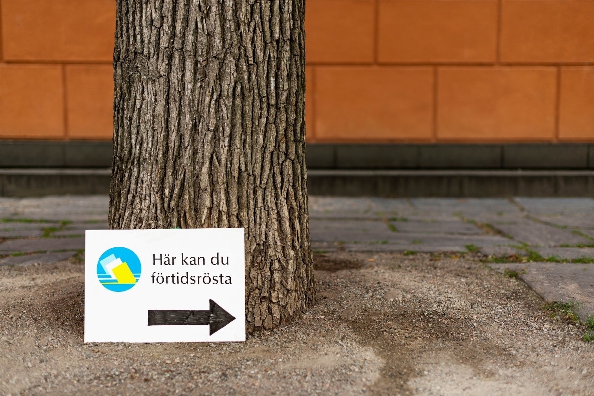 Skylt lutad mot ett träd med texten "här kan du förtidsrösta".