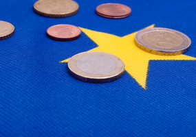 Euromynt liggandes på EU-mönster.