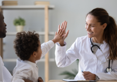 En kvinnlig läkare som ger high-five till ett barn