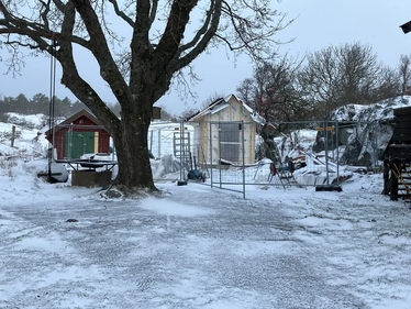 Två små bodar, en rödmålad och en under byggnation, i ett snötäckt landskap.