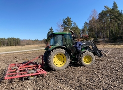 Bilden visar en traktor på en åker.
