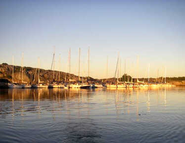 Segelbåtar vid klippor i kvällsljus .