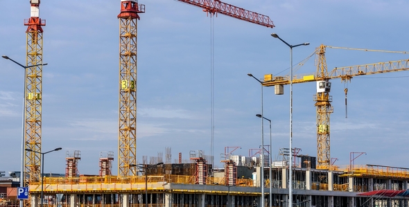 Stort byggarbetsområde med flera kranar mot en klar himmel.