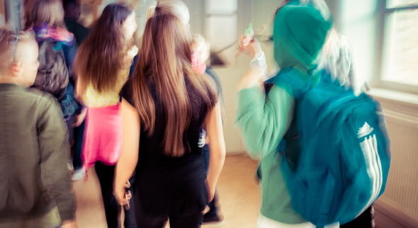 Suddig bild på flera barn i en skolkorridor.