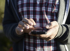 Bilden visar en person som håller i en mobiltelefon.
