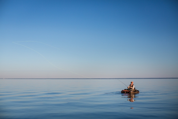 Spegelblankt vatten och en person som fiskar från båt. Foto: Jesper Anhede. 