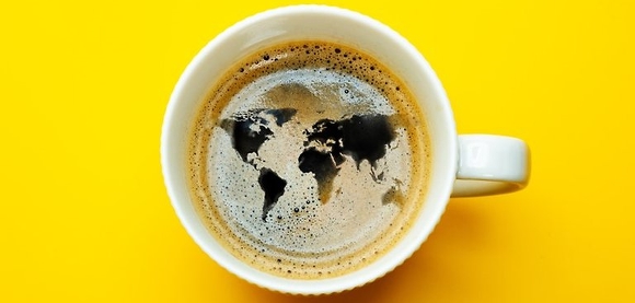 Gul bakgrund med en kaffekopp där skummet formar en världskarta