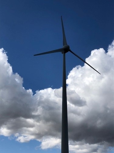 Ett vindkraftverk mot en blå himmel med vita moln.