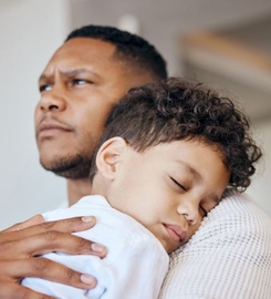 Pojke sover på förälders axel